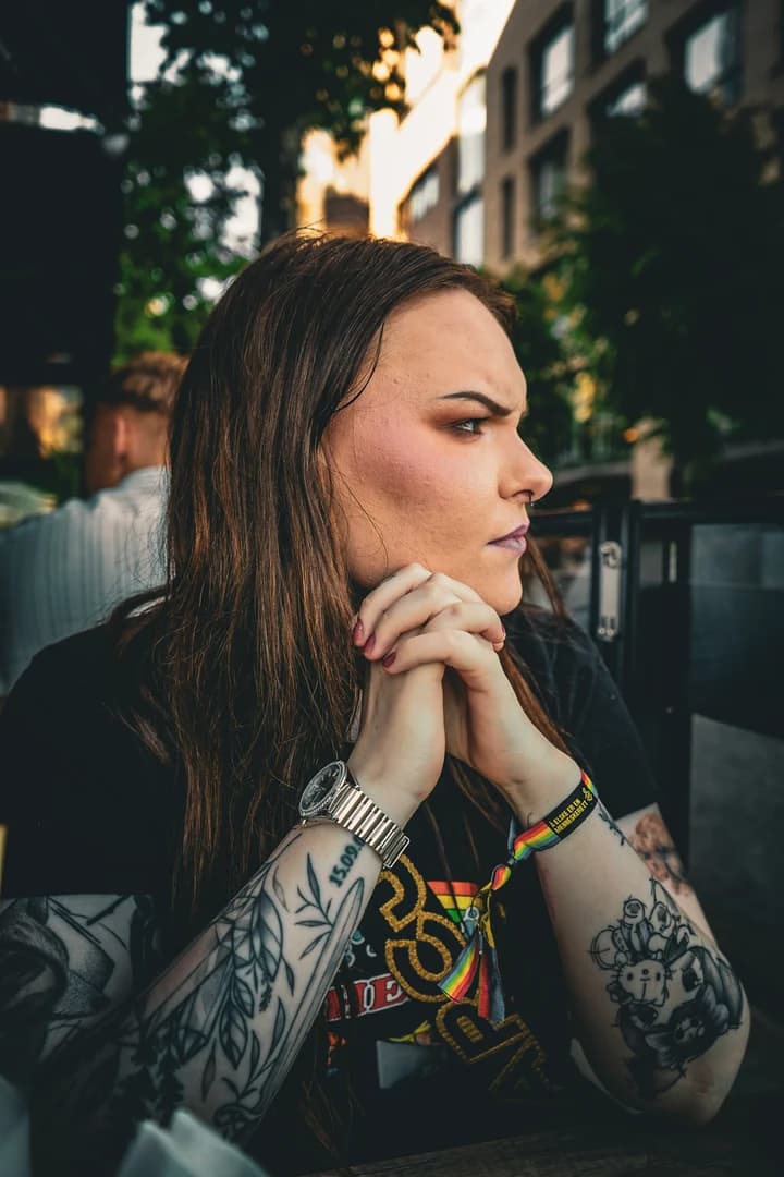 Nært portrett av en tatovert kvinne som ser til siden på en uteservering.